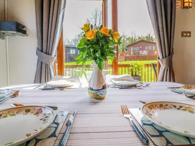 a table with plates and a vase with flowers at 3 The Glade in Wadebridge