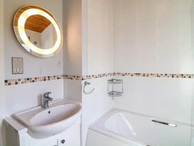 a white bathroom with a sink and a mirror at 3 The Glade in Wadebridge
