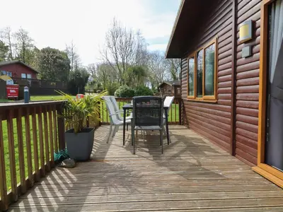 a wooden deck with a table and chairs on it at 3 The Glade in Wadebridge