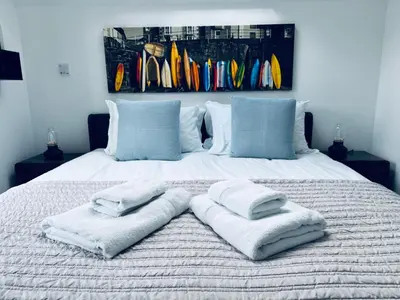 a bed with towels on top of it with surfboards at Uno in the City - Urban Boutique Accommodation in Truro