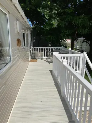 a white porch with a white fence and chairs at Cosy 2 bed pet friendly holiday home Crantock Nr Newquay in Crantock