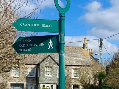 a green street sign in front of a house at Cosy 2 bed pet friendly holiday home Crantock Nr Newquay in Crantock