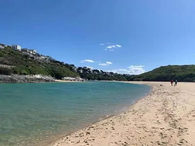 a beach with two people walking on the sand at Cosy 2 bed pet friendly holiday home Crantock Nr Newquay in Crantock
