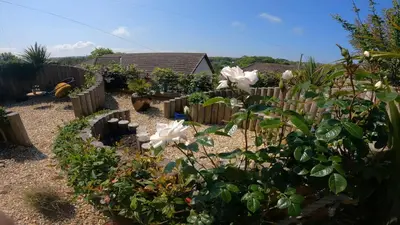 a garden with white flowers and a wooden fence at Gwel-an-Tansys in St. Agnes