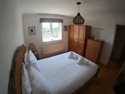 a bedroom with a white bed and a window at Gwel-an-Tansys in St. Agnes
