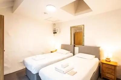 two beds in a room with a mirror at Tregenna Castle Self Catering in St Ives