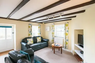 a living room with a black leather couch and a tv at Tregenna Castle Self Catering in St Ives