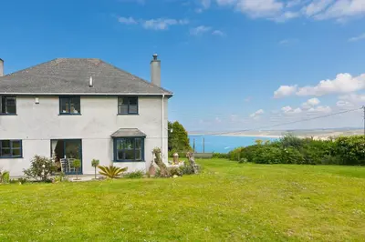 a house on a lawn with the ocean in the background at Lanyon in St Ives