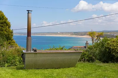 a bath tub sitting in the grass with a view of the ocean at Lanyon in St Ives