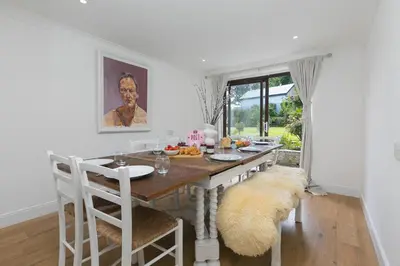 a white dining room with a wooden table and chairs at Lanyon in St Ives