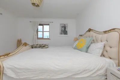 a bedroom with a large white bed with a large headboard at Lanyon in St Ives