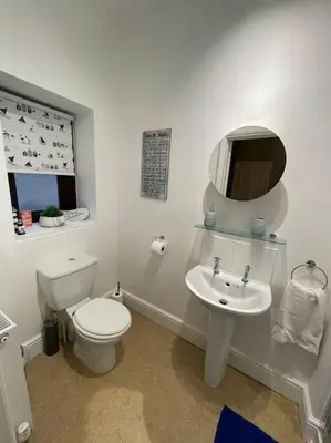 a white bathroom with a toilet and a sink at No1 Cottage Mevagissey in Mevagissey