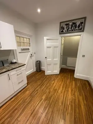 a kitchen with white cabinets and a hard wood floor at No1 Cottage Mevagissey in Mevagissey