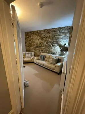 a living room with two couches and a stone wall at No1 Cottage Mevagissey in Mevagissey