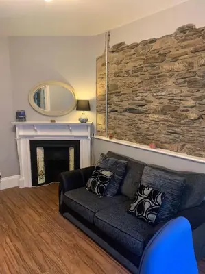 a living room with a couch and a stone wall at No1 Cottage Mevagissey in Mevagissey