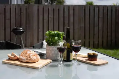 a table with two glasses of wine and bread at The Old Shop in Withiel Village with private enclosed garden in Withiel