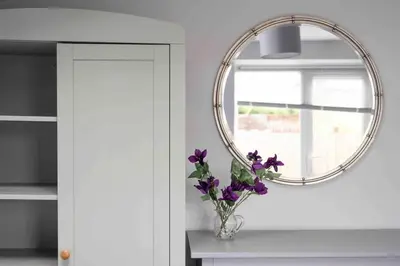 a vase of purple flowers on a table with a mirror at The Old Shop in Withiel Village with private enclosed garden in Withiel