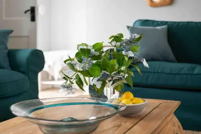 a vase with flowers and a bowl of lemons on a table at The Old Shop in Withiel Village with private enclosed garden in Withiel