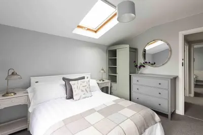 a white bedroom with a bed and a mirror at The Old Shop in Withiel Village with private enclosed garden in Withiel