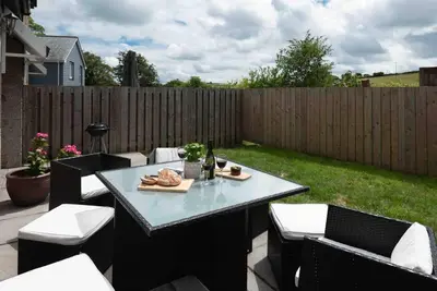 a patio with a table and chairs and a fence at The Old Shop in Withiel Village with private enclosed garden in Withiel
