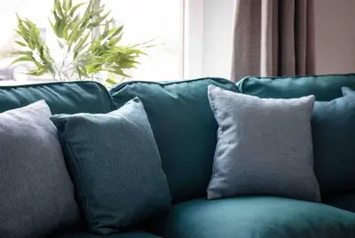 a green couch with three pillows on it at The Old Shop in Withiel Village with private enclosed garden in Withiel