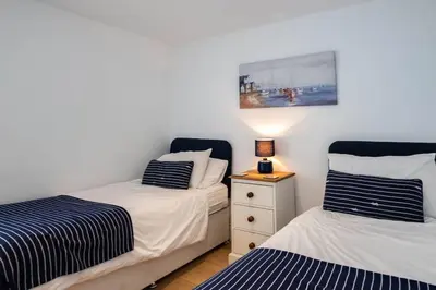 a bedroom with two beds and a lamp on a night stand at Derowen, Port Isaac Bay Holidays in Port Isaac