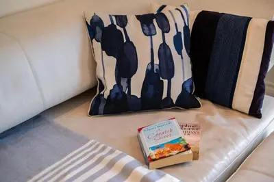 a book sitting on top of a couch with a pillow at Derowen, Port Isaac Bay Holidays in Port Isaac
