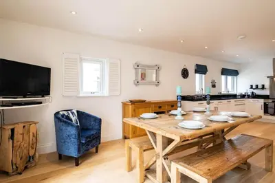 a dining room with a wooden table and a blue chair at Derowen, Port Isaac Bay Holidays in Port Isaac