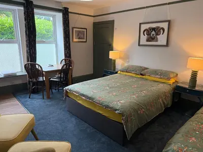 a bedroom with a bed and a table and chairs at Highermead House in Camelford