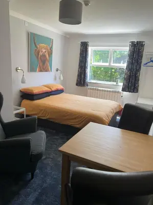 a room with two beds and a cow painting on the wall at Highermead House in Camelford