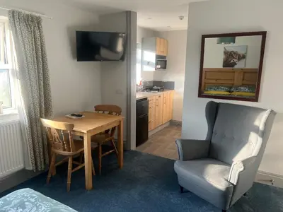 a room with a table and a chair and a kitchen at Highermead House in Camelford