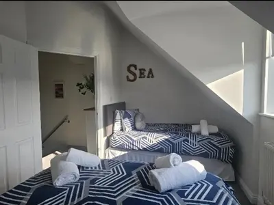 two beds with towels on them in a bedroom at Perran Beach House in Perranporth