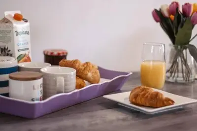 a table with a tray of pastries and a glass of orange juice at Perran Beach House in Perranporth