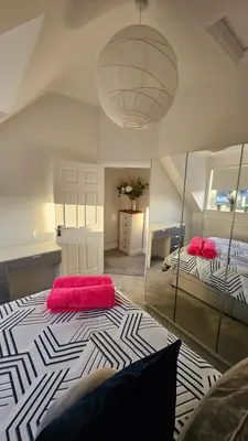 a large room with two beds and a large mirror at Perran Beach House in Perranporth