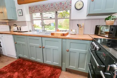 a kitchen with blue cabinets and a sink and a window at Little Wren Cottage in Marazion