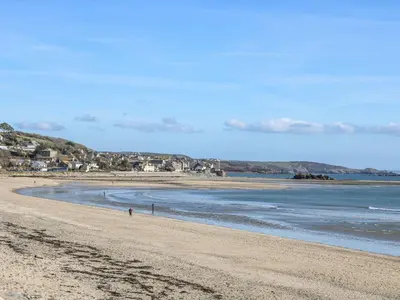 a beach with a person walking on the sand at Little Wren Cottage in Marazion
