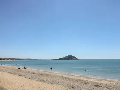 a beach with a group of people in the water at Little Wren Cottage in Marazion