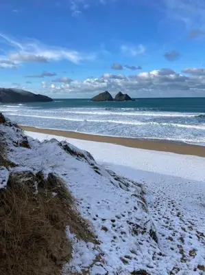 a beach with snow on the sand and the ocean at Cubert Nr Newquay Traditional 16th century cottage in Cubert