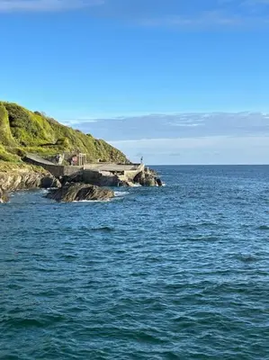 a bridge over a body of water next to the ocean at Cubert Nr Newquay Traditional 16th century cottage in Cubert