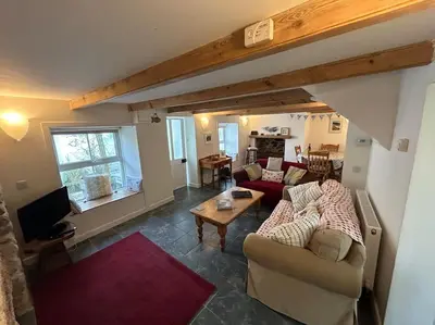 a living room with two couches and a table at Cubert Nr Newquay Traditional 16th century cottage in Cubert