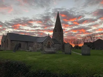 an old church in a field with a sunset at Cubert Nr Newquay Traditional 16th century cottage in Cubert