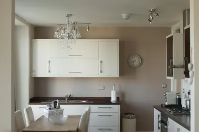 a kitchen with white cabinets and a table and a chandelier at Fairfield Apartment in St Ives