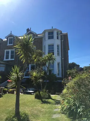 a large house with palm trees in front of it at Fairfield Apartment in St Ives