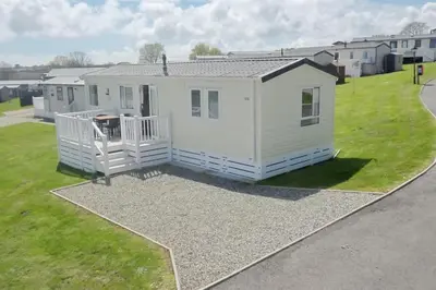 a small white house on a patch of grass at Holiday Home - St Austell in St Austell