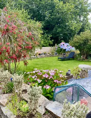 a garden with flowers and a bench in the background at Detached Home Close to the Beach Newquay in Saint Columb Minor