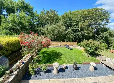 a garden with a bench and flowers and rocks at Detached Home Close to the Beach Newquay in Saint Columb Minor