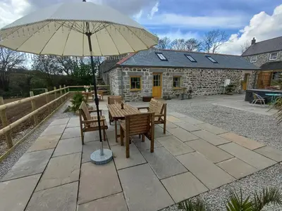 a table and chairs under an umbrella on a patio at Luxury countryside retreat with hot tub in Leedstown