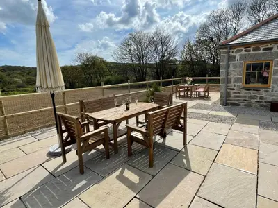 a wooden table and chairs on a patio with an umbrella at Luxury countryside retreat with hot tub in Leedstown