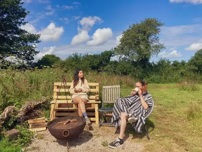 a man and a woman sitting on a bench at Foxglove Field Glamping in Perranuthnoe