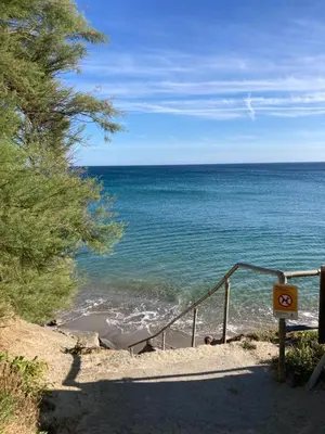 a view of the ocean from a beach with a staircase at Foxglove Field Glamping in Perranuthnoe
